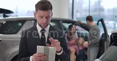自信的年轻白种人男子使用平板电脑作为家庭交谈的背景。 成功的汽车经销商